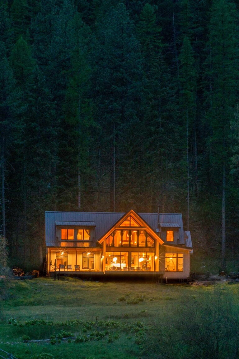 The Minam River Lodge at night, viewed from a distance with interior lights illuminating the surroundings.