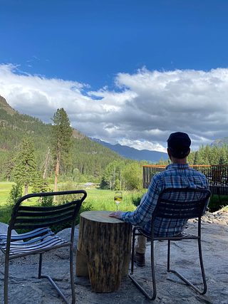A man with a glass of wine seated outside Minam River Lodge.
